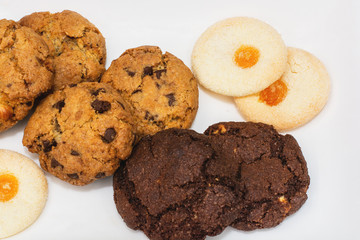 Top view of a plate of oatmeal chocolate, shortbread cookies on a white background