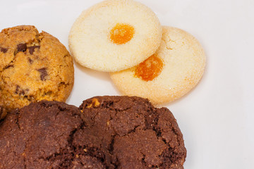 Top view of a plate of oatmeal chocolate, shortbread cookies on a white background