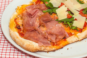Fresh baked pizza with melted cheese, Italian herbs and tomato sauce and fresh basil on a white plate on a red white background. Italian food, menu, restaurant concept