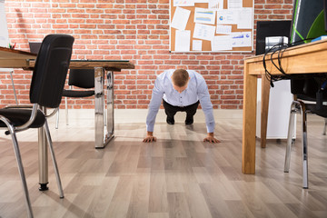 Businessman Doing Push Up In Office