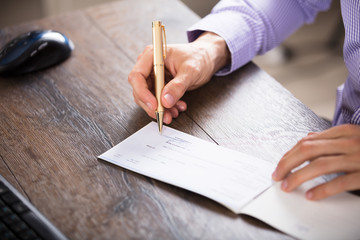 Businessperson's Hand Signing Cheque