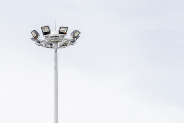 Close up sportlights tower in stadium with blue sky in background.