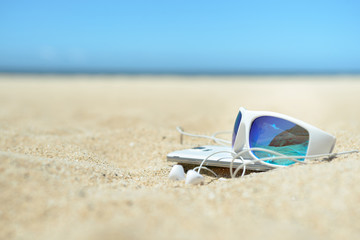 Fototapeta na wymiar Sunglasses and phone on the beach