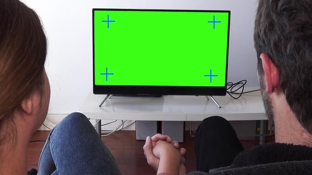 Loving Couple Watching Television Together Zoom Out From Green Screen. Couple watching television green screen relaxed at home. Zoom out behind models shoulders