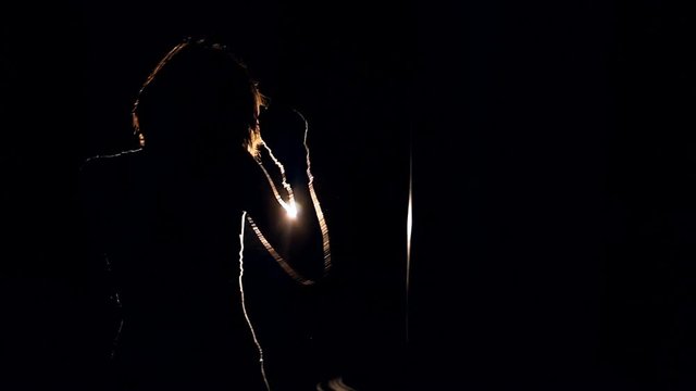 Mid shot of a girl boxing actively in the dark with a single projector.