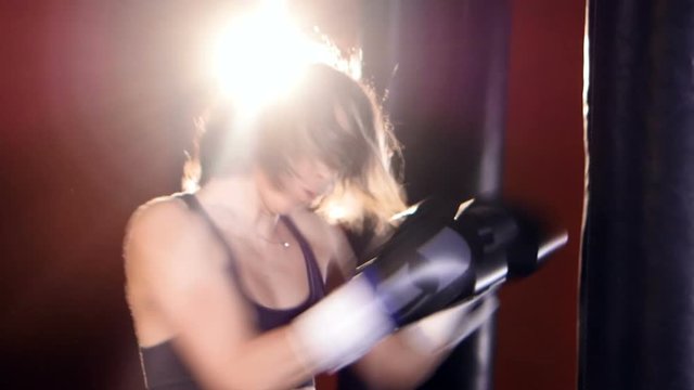 Close up of the woman boxing with punching bags. 