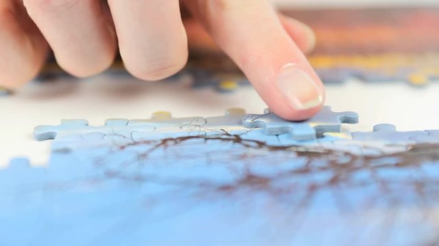 Putting jigsaw puzzle piece in place closeup 4K