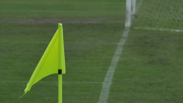 The yellow corner flag waving in the wind on the stadium.