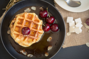 Honey on waffles with cherry berries on dark wooden background. breakfast concept