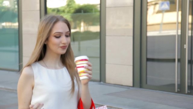 Young blonde girl with happy smile holding many shopping bags and drink coffee