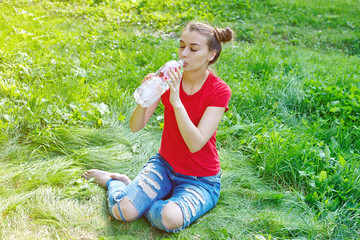 Young woman drinks water outdoors