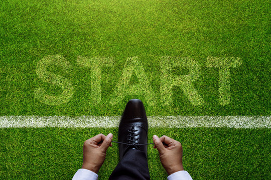 Top view of Businessman tie his shoes over Start line in soccer grass field with Start word background, Business Challenge or do something new concept