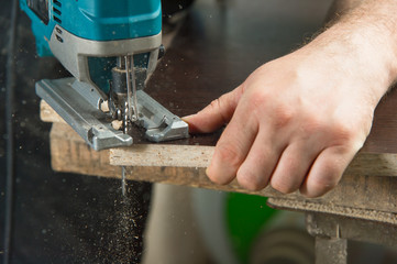 Close-up carpenter working with an electric jigsaw