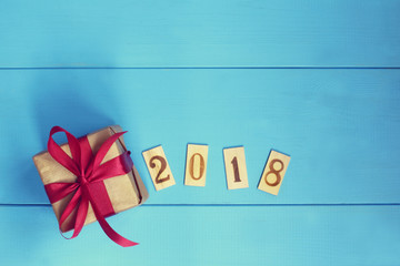 festive surprise 2018/ Gift with red ribbon and wooden figures top view 