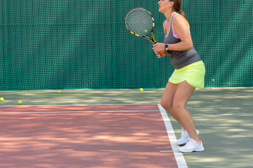 Young sportswoman playing on tennis court