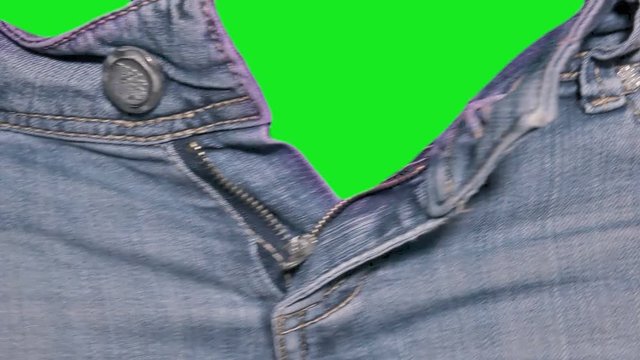 The hands of a woman opening the zipper of a pair of jeans, revealing a green chroma key ready background. Close-up detail shot.
