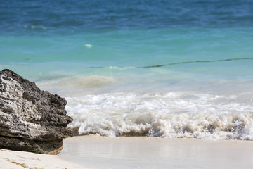 Fototapeta na wymiar Coastline on the Caribbean ocean. White sand beach and turquoise waters. Small waves hitting the shore.