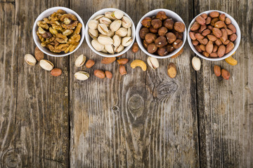 Four bowls with nuts on a  wooden table