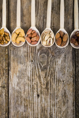 Nuts in a wooden spoons on a  wooden table.
