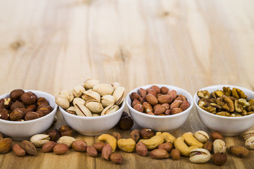 Four bowls with nuts on a  wooden table