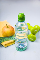 Dumbbells, an apple, a towel and a bottle of water