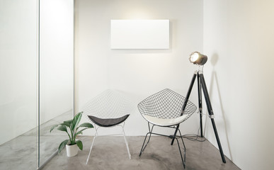 Empty office waiting room.Loft interior style , white canvas print on the center white wall. Two black and white chairs at the concrete floor .