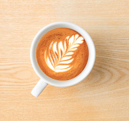 Time for espresso.Above capture of white coffee cup with tree shape latte art on wood table at cafe