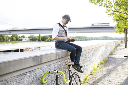 Businessman with bicycle and tablet at the riverside