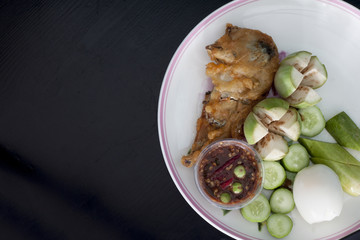 Thai menu Fried mackerel with shrimp paste sauce with boiled egg on wood black background.