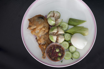 Thai menu Fried mackerel with shrimp paste sauce with boiled egg on wood black background.
