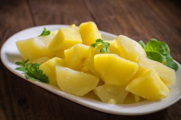 Boiled potatoes with rocket salad. Wooden background. Top view. Close-up