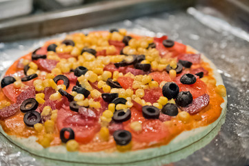 Mexican and American pizza. Pizza with tomatoes, sausage, corn, cheese, olives. Homemade pizza. Pizza on foil