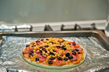 Mexican and American pizza. Pizza with tomatoes, sausage, corn, cheese, olives. Homemade pizza. Pizza on foil