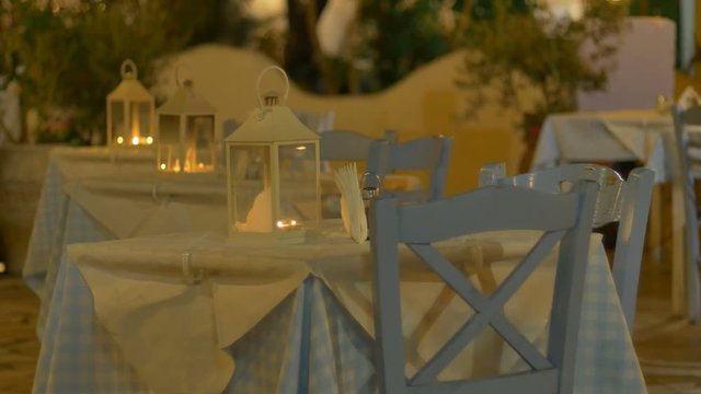 Blue and white tablecloth and tables and chairs in the night in Greece.