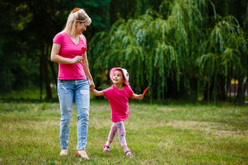 Fototapeta premium mother and daughter are in park in sunny colorful day and eat lollipop