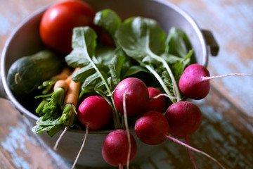 Fresh farm vegetables in bowl. Radish, carrot, cucumber and tomato on old wooden rustic background. Toned photo