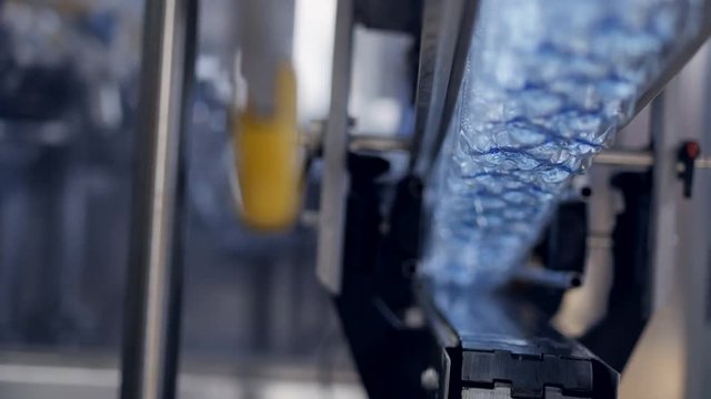 Fast moving empty bottles transferred above conveyor belt. 