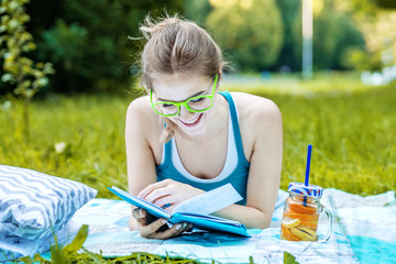 Smart girl reading an interesting book in the park. The concept of education and lifestyle.