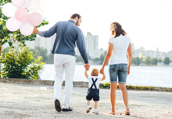 Fototapeta premium Baby's first steps with mom and dad on the street