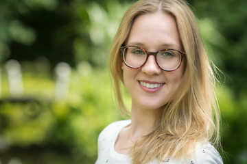 Fototapeta premium Frau mit Brille im Portrait - Lächelnde Frau mit Brille im Frühling