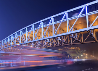 Obraz premium Pedestrian bridge with traffic in motion blur at night, Beijing center, China