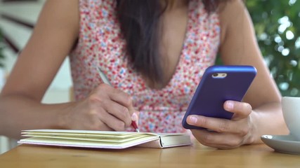 Woman learn english using mobile smartphone and writing in notebook.