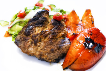 Fried meat on the grill. Fried meat on coals. Steak, fried vegetables, pepper
