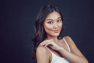 Portrait of a beautiful asian woman with makeup and light curls on black background.