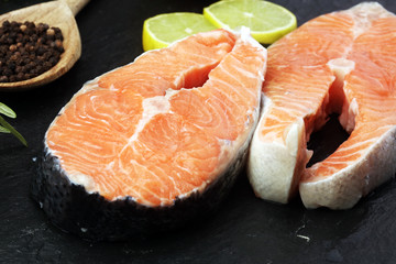 Fresh raw salmon fish steaks with fresh herbs on stone background