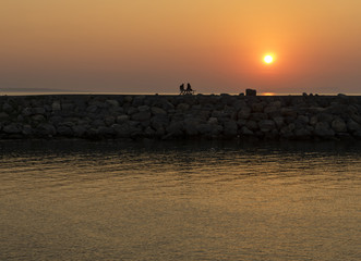 Fototapeta na wymiar lovers sitting on the wharf at the sunset