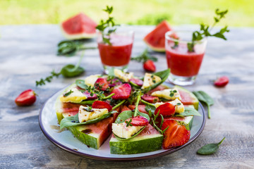 Delicious watermelon pizza with cheese and herbs on a table in the garden
