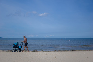 a man walks with his baby on the beach