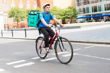 Courier On Bicycle Delivering Food In City