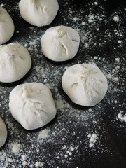 Raw khinkali, Georgian traditional dish, covered with flour on a dark wooden board